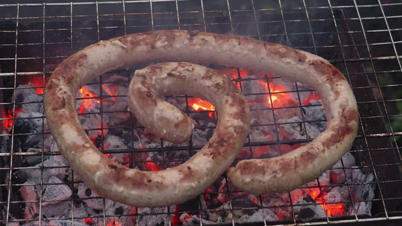 Grigliata di salsiccia su carboni ardenti su un barbecue