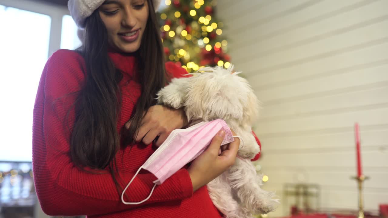 mujer con un perro con una máscara durante la navidad