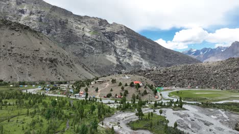 drone aéreo giratorio disparado sobre casas de la aldea en la cima de una colina con el río indo fluyendo a lo largo del valle de basho, rodeado por la cordillera en skardu, pakistán