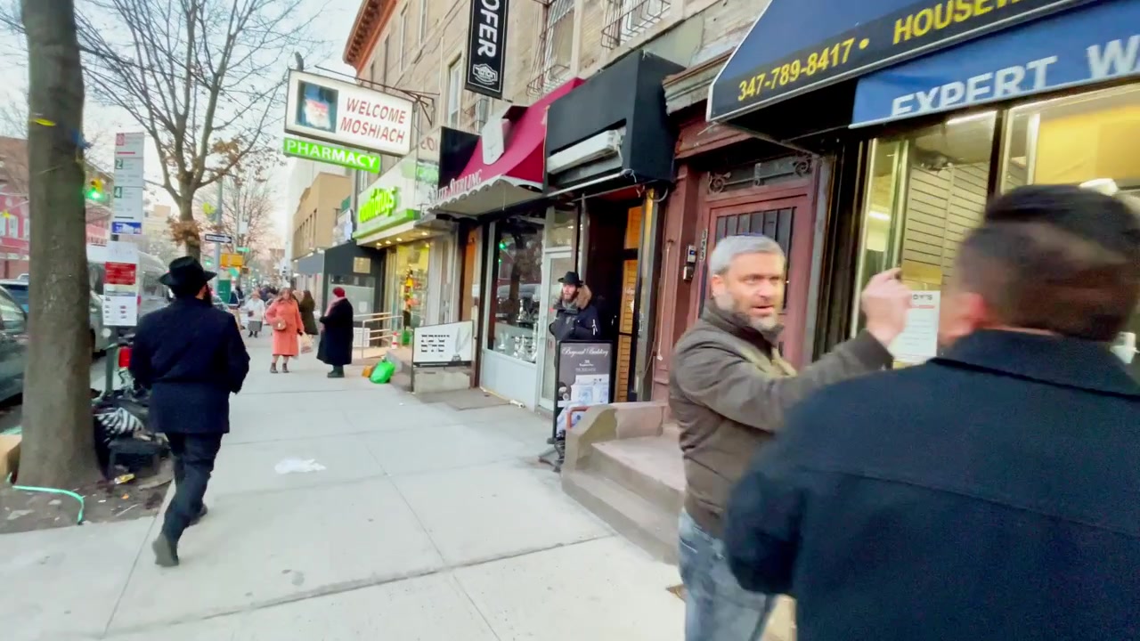New York, USA, 9 marzo 2022: Pedoni che camminano davanti a negozi al dettaglio e vetrine su un viale cittadino