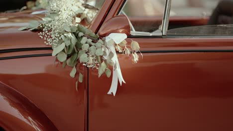 classic vehicle adorned with greenery and ribbon on door for celebration