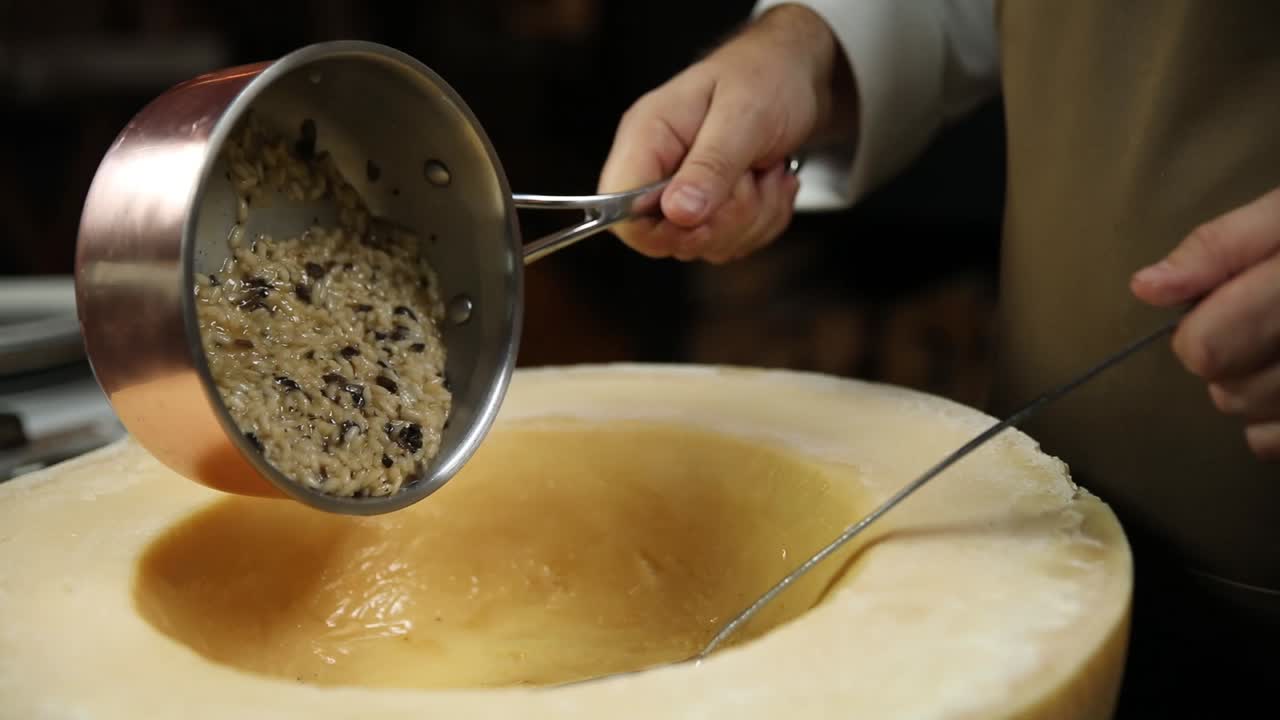 Chef preparing risotto in a large parmesan cheese