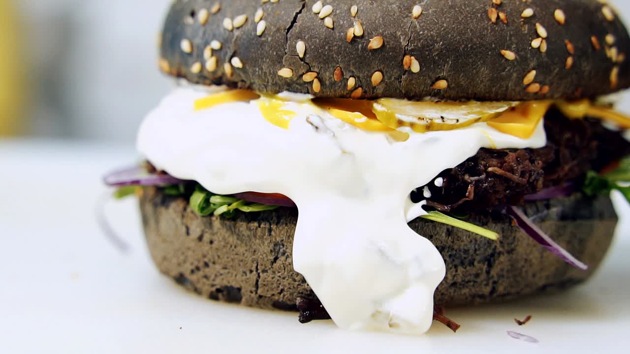Veggie hamburger. Delicious black burger with organic ingredients. Juicy dark hamburger with white sauce. Macro shot