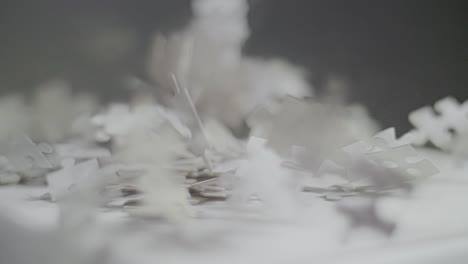 slow motion: white and gray puzzle pieces falling on a white surface and bouncing and spinning back with a dark background. close up with shallow depth of field. shot in 4k
