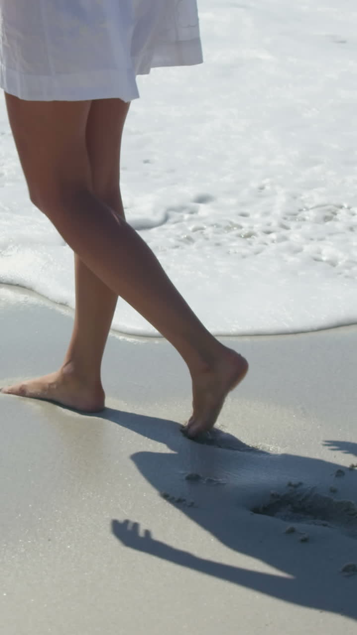 Donna che cammina sulla spiaggia a piedi nudi