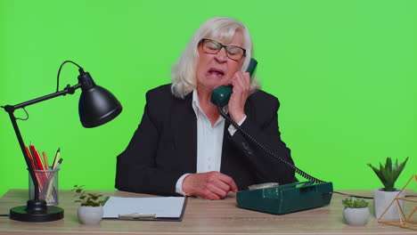 crazy senior businesswoman talking on wired vintage telephone fooling making silly humor comic faces