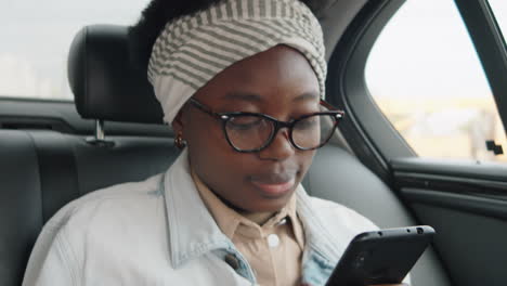 african american woman using smartphone during car ride