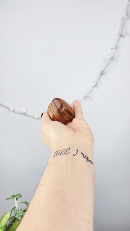 hand holding a stone with 'still i rise' tattoo