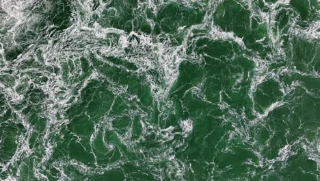 aerial top down shot of stormy waves moving in ocean during sunny day