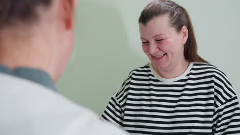 expectant mother excited and smiling while receiving pregnancy result from doctor, joyful reaction to positive news after consultation. patient happy and emotionally engaged in the result