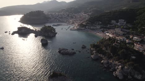 Vista-Aérea-Cinematográfica-De-La-Costa-Y-La-Ciudad-De-Parga-Con-El-Sol-Reflejado-En-El-Mar-Jónico