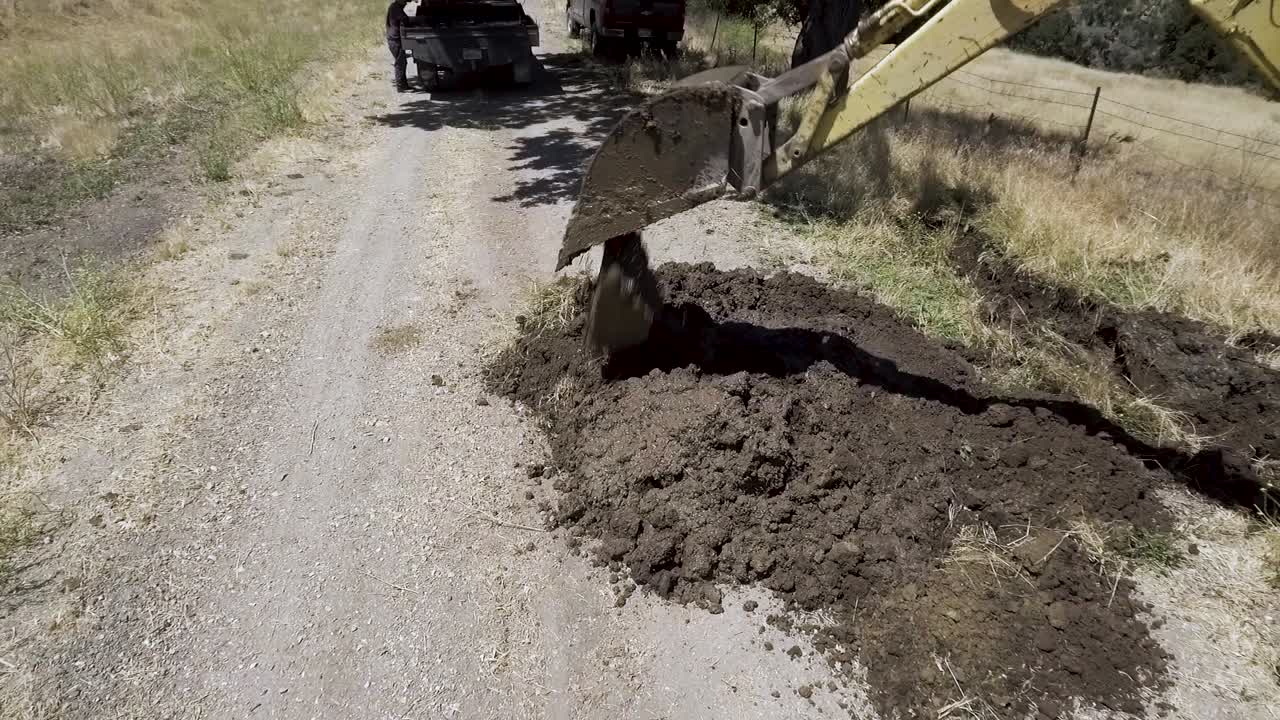 tractor retroexcavadora desenterrando una línea de agua con fugas en un día caluroso-2