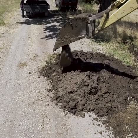 backhoe tractor digging up a leaking water line on a hot day-2