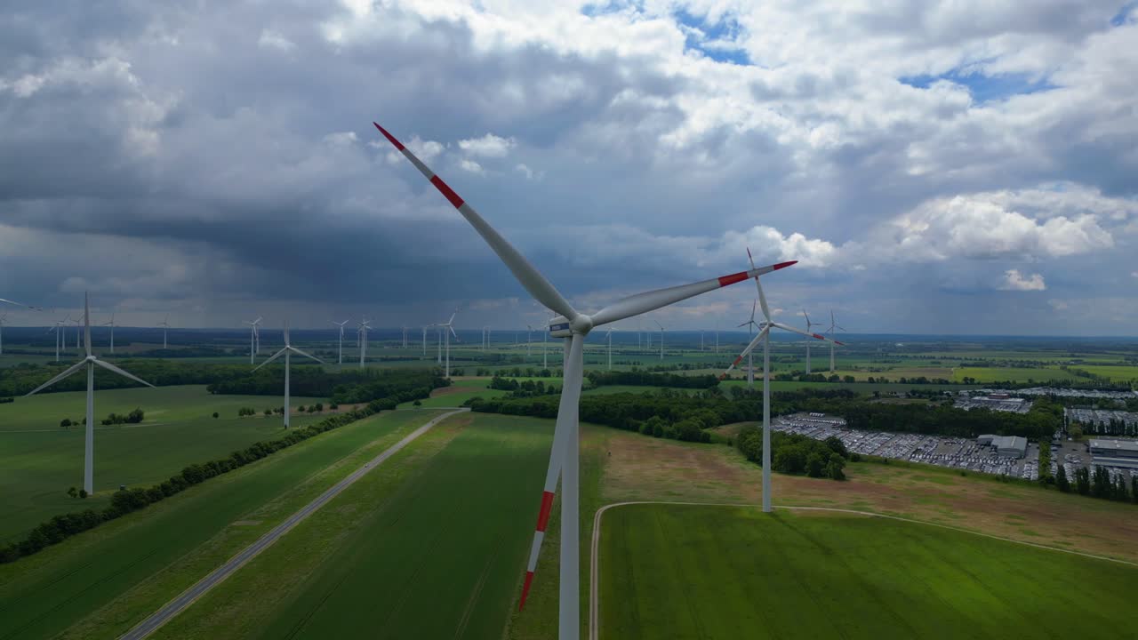 Wind turbines generating clean energy in a large wind park in Germany, under a cloudy sky. Dramatic aerial view flight panorama overview drone