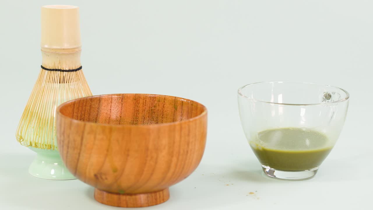 Glass cup with matcha tea, water poured in, minimal clean background, soft even lighting