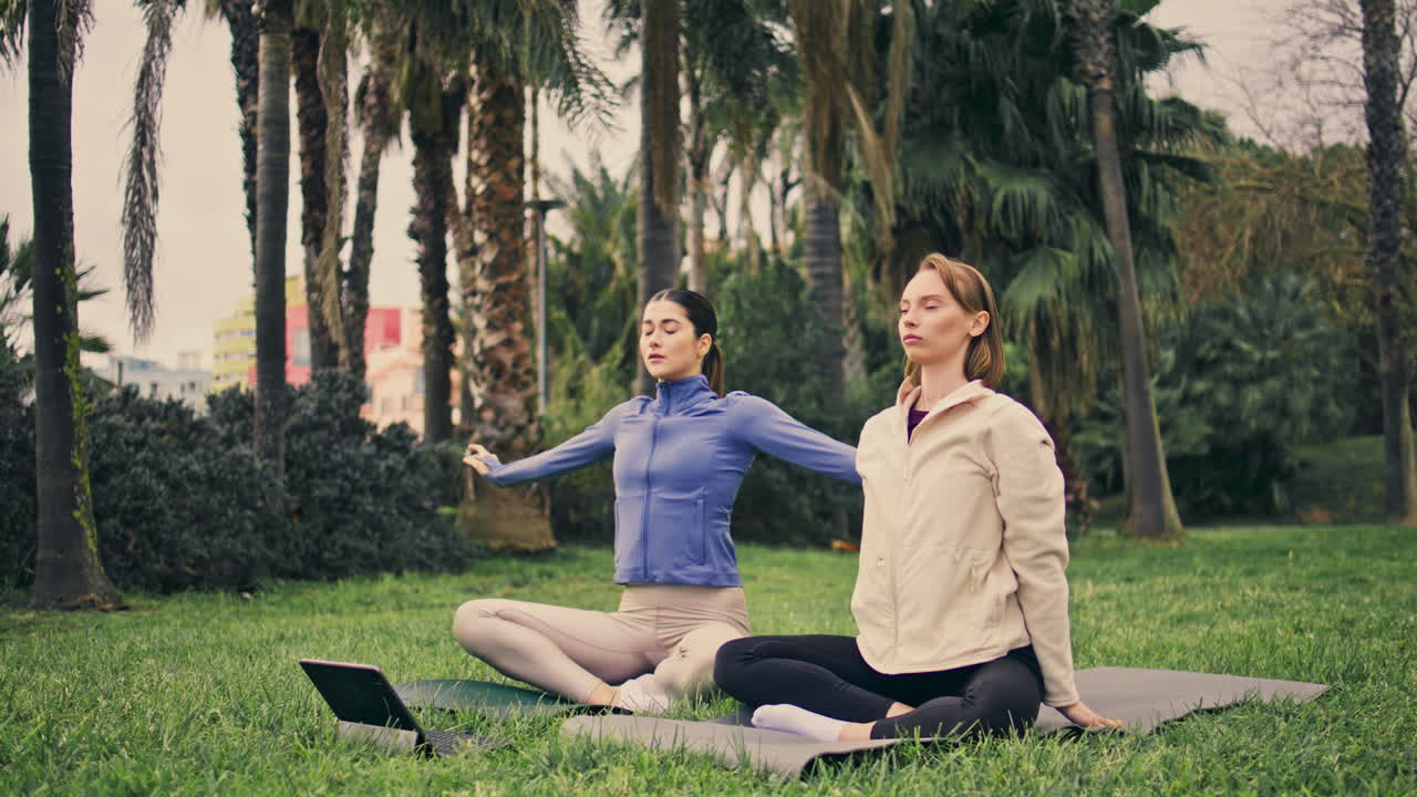 평온한 여자들이 롯스 위치에 앉아 손바닥 장소. 편안한 스포츠 여성 온라인 요가