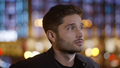 Focused-man-looking-around-outdoors.-Young-man-standing-on-night-city-street