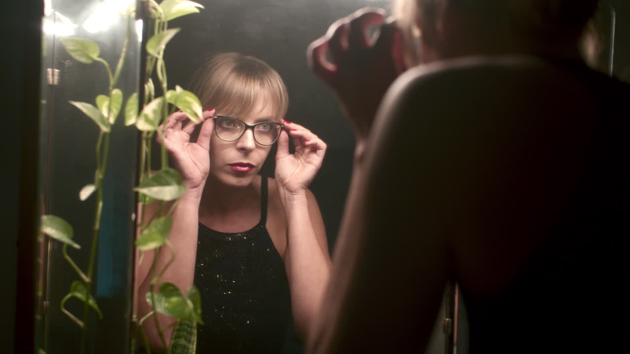 Woman adjusting glasses in front of mirror