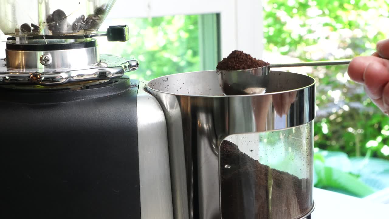 Utilizing a top-tier burr grinder to process freshly roasted coffee beans into a medium consistency. Pulverizing premium coffee beans in a sleek, industrial-grade black Perfect hot cup of hot coffee..