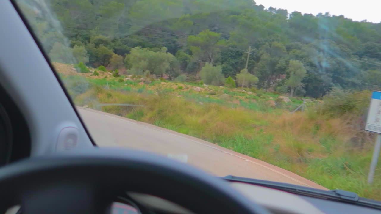 운전자가 언덕이 많은 지역에서 지그재그로 회전하는 동안 자동차 조향 장치와 대시보드를 자세히 볼 수 있습니다.