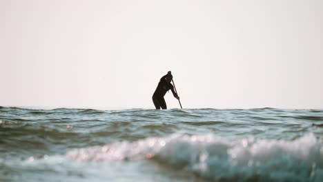 A-lone-paddle-boarder-surfing-at-dusk-in-Tofino,-British-Columbia