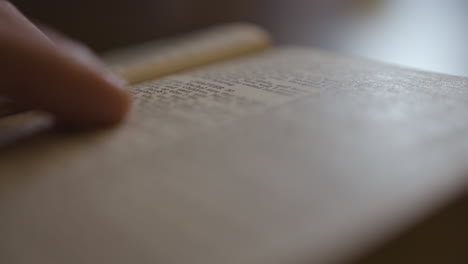 extreme close up of the bible as someone fingers through the pages reading