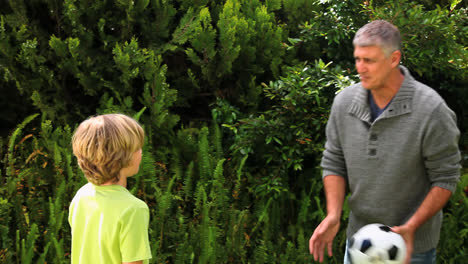 Padre-E-Hijo-Jugando-Al-Fútbol-En-El-Jardín