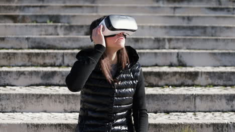 Young-dark-haired-woman-in-warm-black-waistcoat-wearing-virtual-reality-glasses-in-early-autumn-park