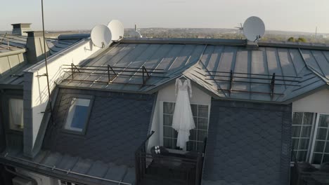 Vestido-De-Novia-Colgado-En-La-Puerta-De-La-Terraza-Del-Balcón-Esperando-A-La-Novia-En-Una-Mañana-Soleada,-Vista-Aérea