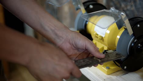 Electric sharpener and blade close up, hands cutting knife
