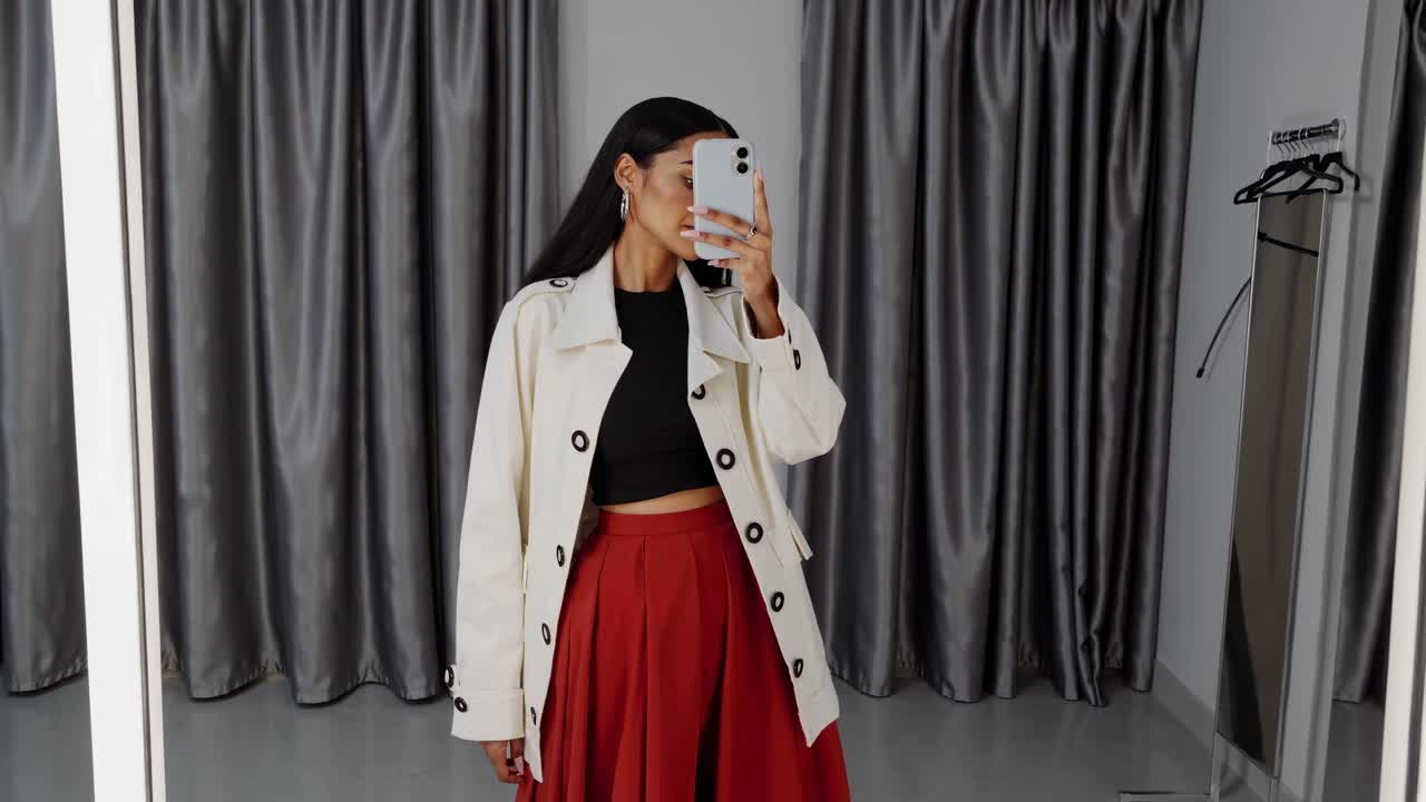 여자 가 착용실 에서 옷 을 착용 하고 있다