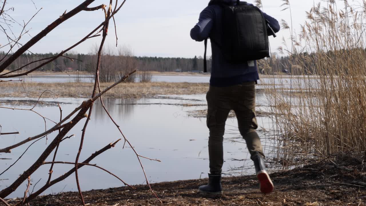 Fotograferende vandrer holder pause og kigger efter fugleliv ved en sumpsø