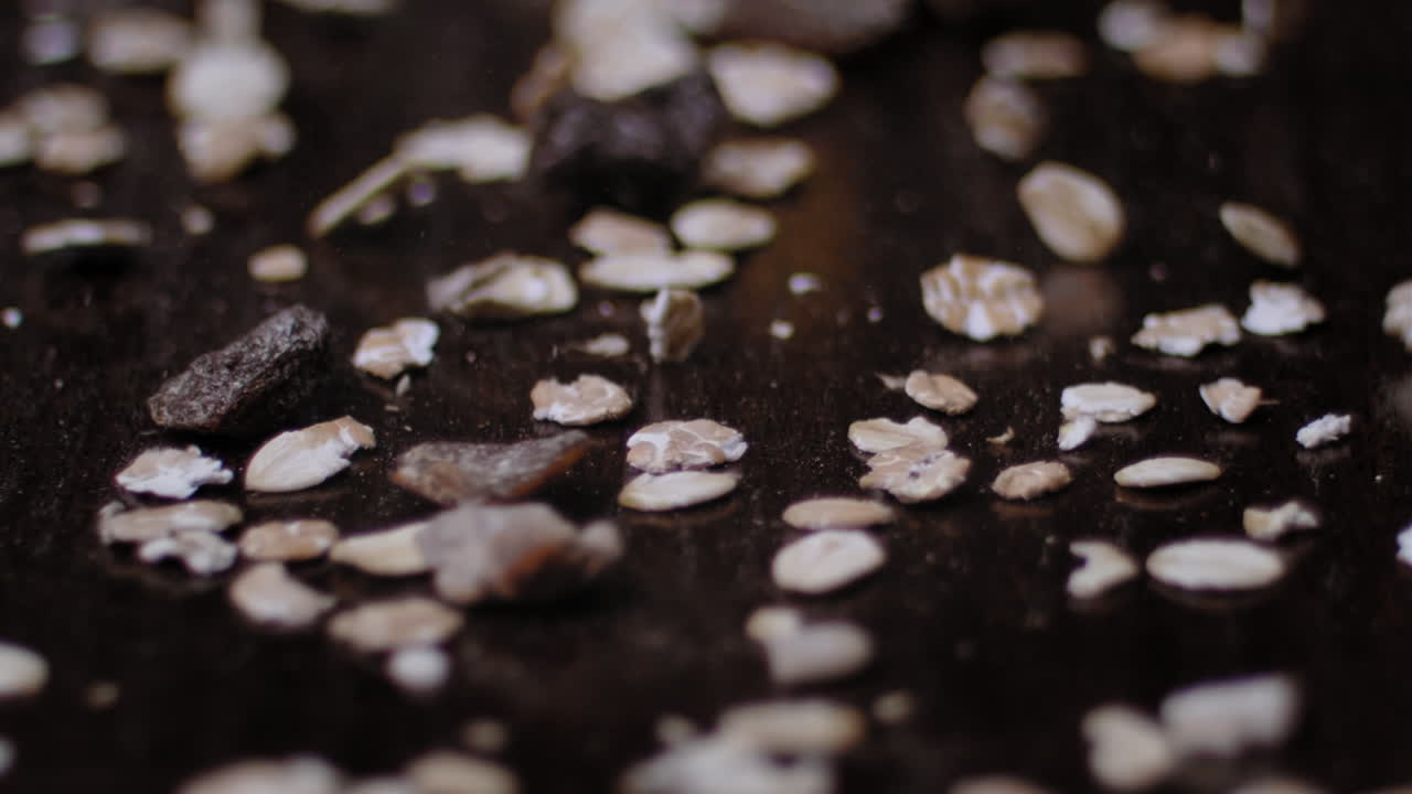 Cereals falling on a dark wooden surface. Low depth of field. High quality slowmotion 240fps.