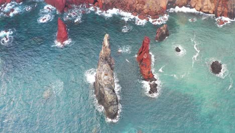 aerial view, sharp rock formation under cliffs above atlantic ocean, picturesque coastline of madeira island, portugal, drone shot