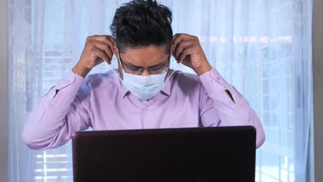 hombre con máscara trabajando en una computadora portátil
