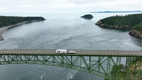 tracking shot of a truck hauling an rv over deception pass in washington state