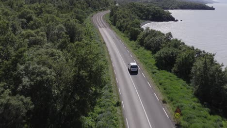 White-car-driving-on-remote-road-in-Iceland-through-natural-forest-and-lake