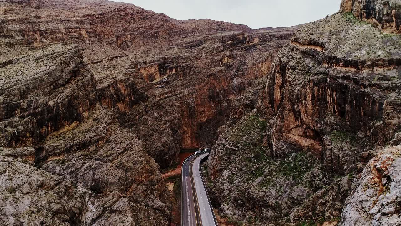 İHA ileri doğru uçar ve dik kayalık kanyonlardan geçen otoyolun üzerinde yükselir