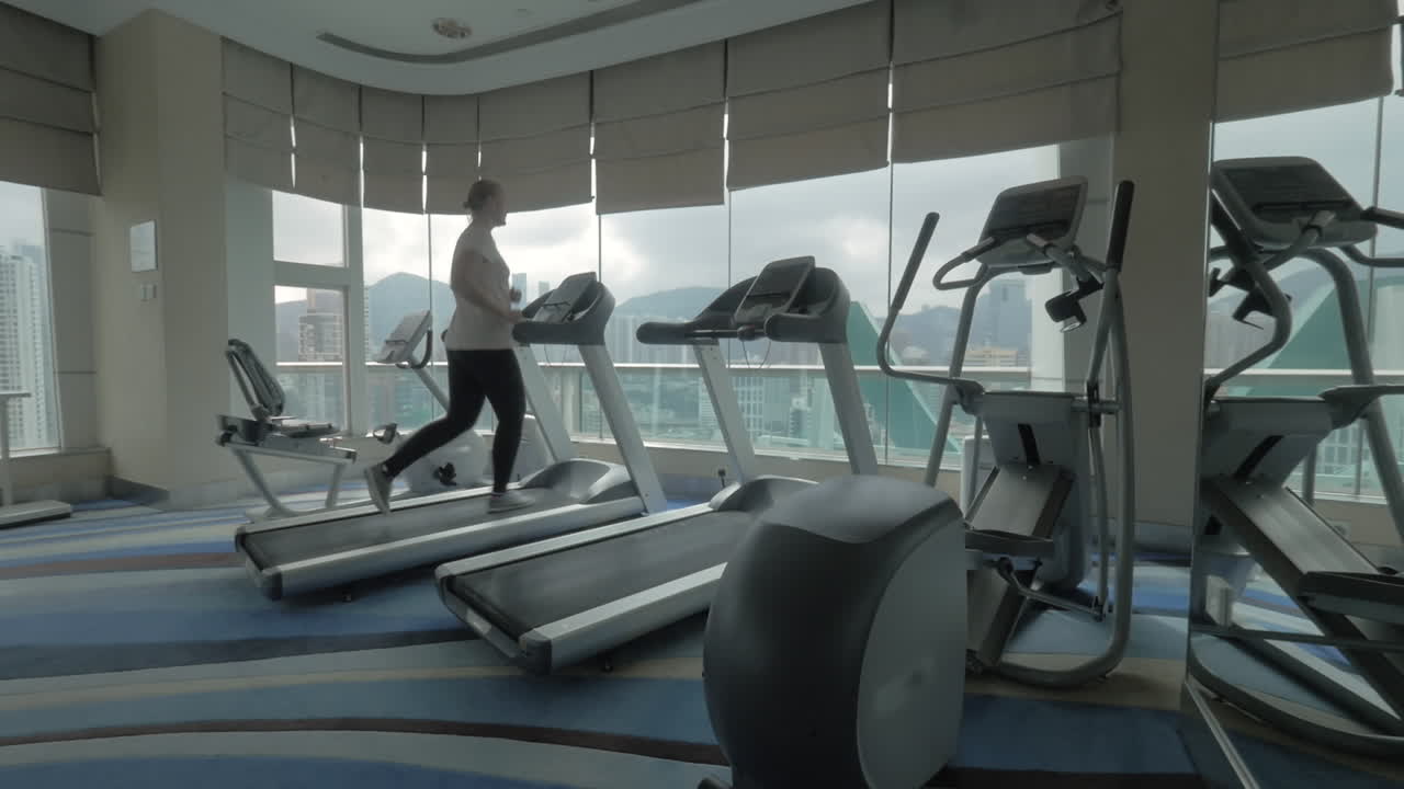 Woman working out on running machine and looking at city