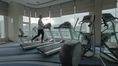 woman working out on running machine and looking at city