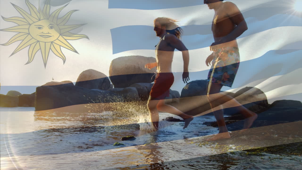 Animation of waving uruguay flag over group of diverse friends running and having fun at the beach