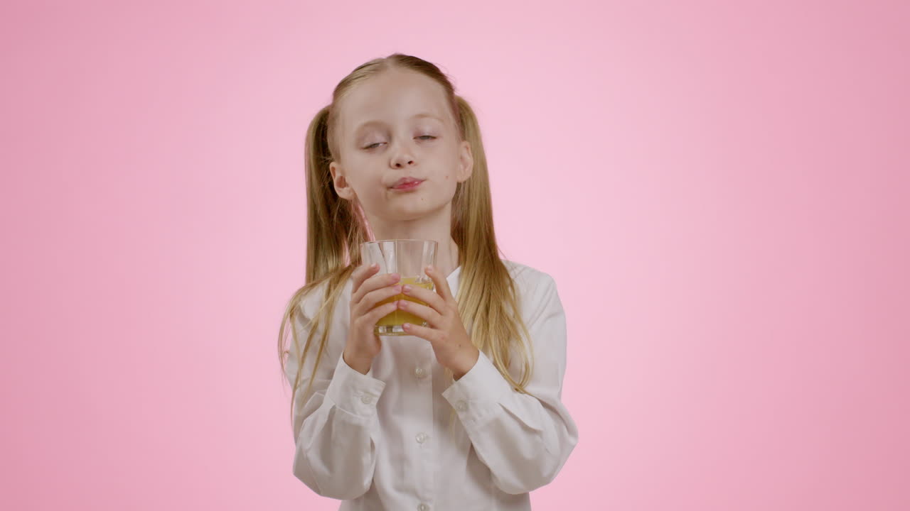 Una chica bebiendo jugo de naranja.