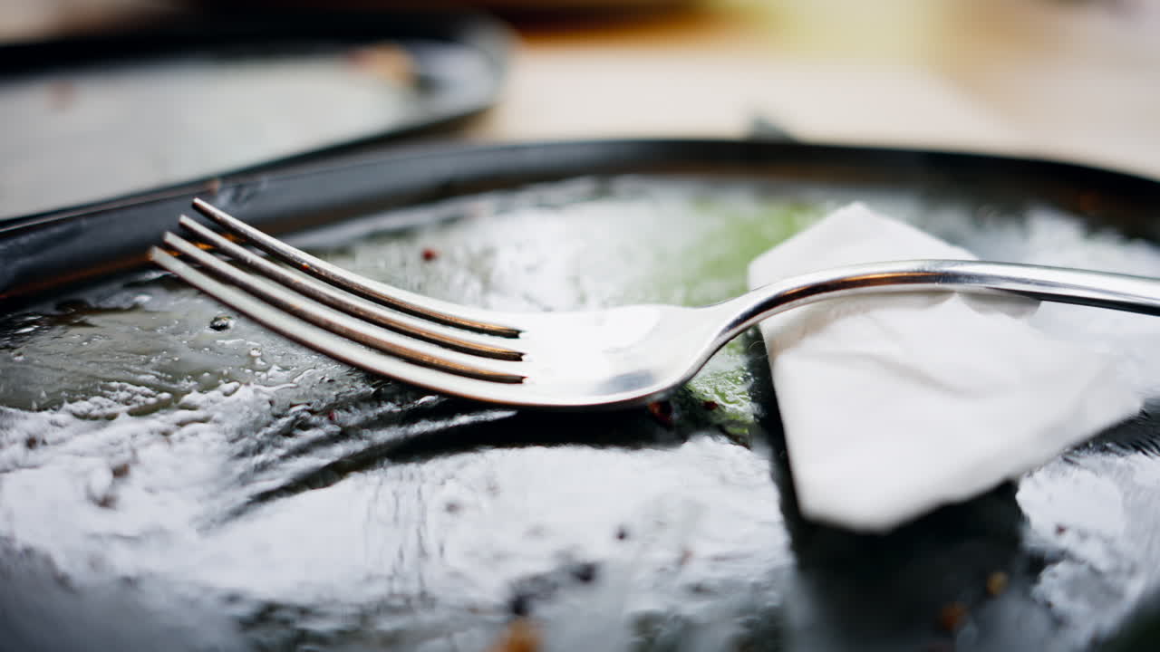 Close up of a steel fork on a paper towel and a black plate
