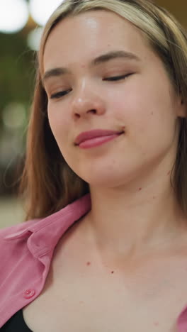 dama de vestido rosa sonriendo con la cabeza inclinada hacia atrás en una postura relajada mueve su cabeza alrededor, disfrutando de un momento de paz y satisfacción, con efecto de luz borrosa en el fondo