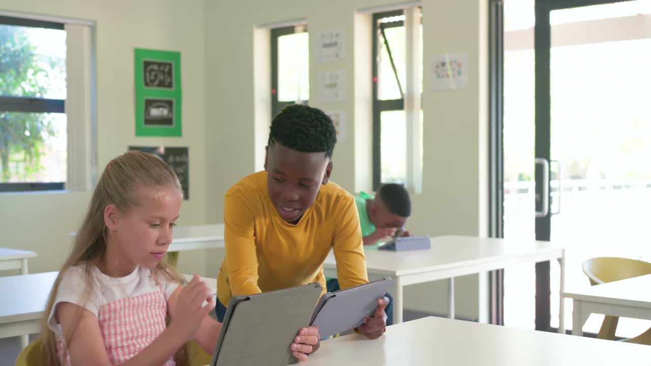 Écoliers utilisant des tablettes en classe, garçon en t-shirt jaune trouvant la réponse et montrant la solution