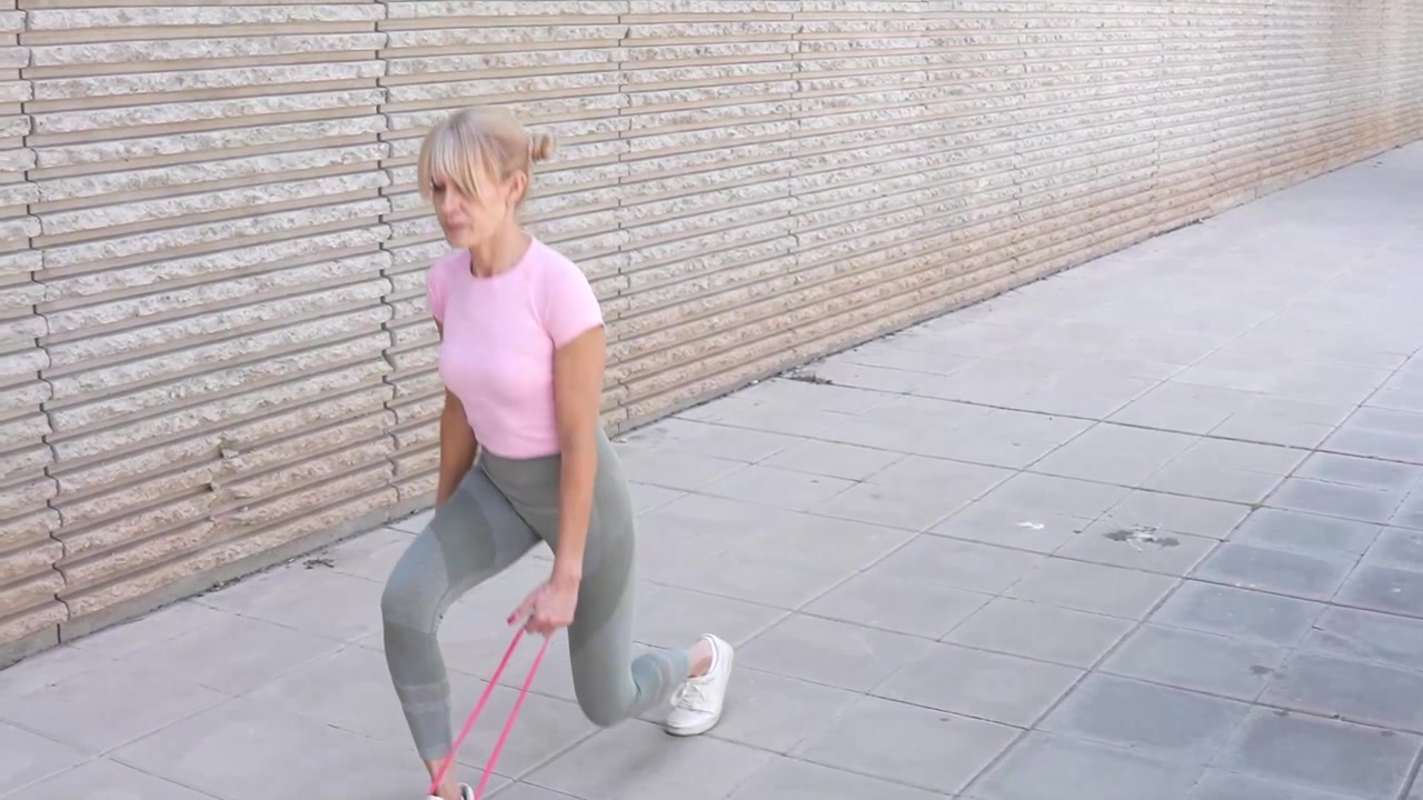 A woman in the city uses resistance bands showing determination and dedication to her fitness