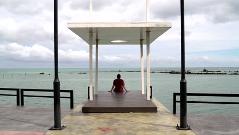 a man sits on a pier and looking at the sea