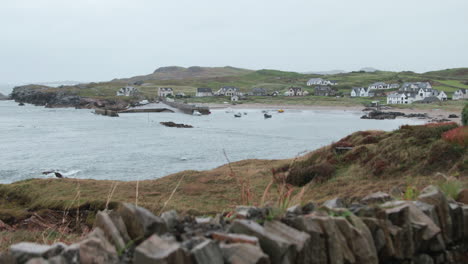 nestled along the coast of county donegal, this quaint village showcases boats anchored in a serene bay, framed by rolling green hills and stunning scenery.