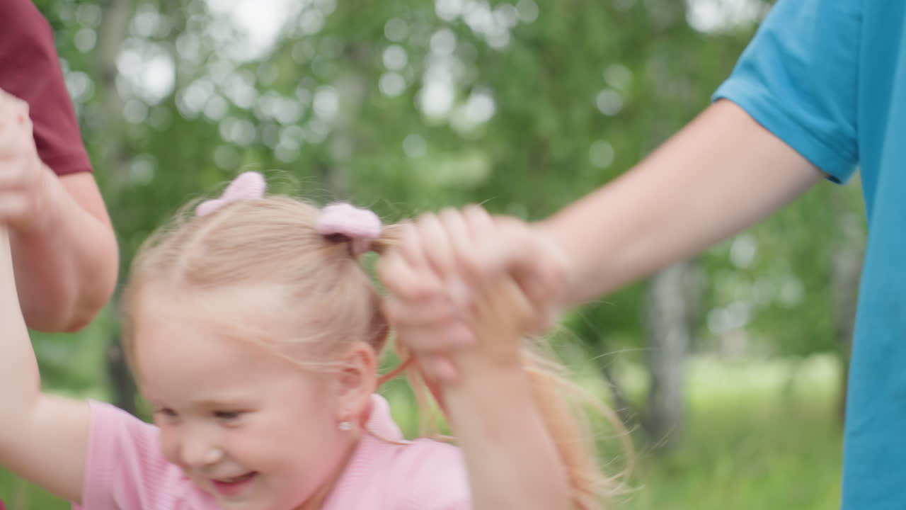 Mãe caucasiana guiando as crianças por um parque de bétulas, segurando-as pelas mãos com carinho e dando passos delicados, menino de azul e menina com rabinhos de cavalo, blusa quente cor de vinho, plano de fundo com árvores verdes, momento espontâneo de união familiar