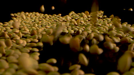 green lentils falling in slow motion on a black mirrored surface